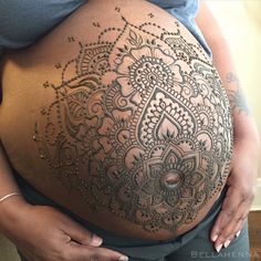 a pregnant woman's belly with intricate designs on it, and the stomach is covered in tattoos