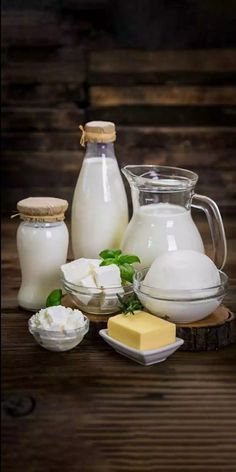 milk, cheese and butter are sitting on a wooden table with other items around it