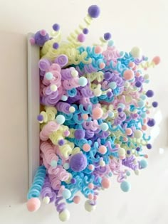 an art piece made out of plastic beads on a white wall with holes in the middle