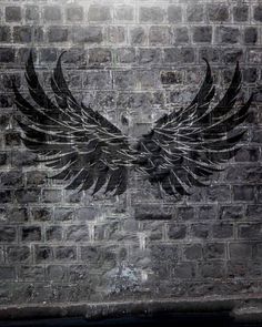 a brick wall with black wings painted on it