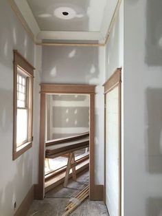 an empty room with unfinished walls and wood trim on the ceiling, along with two windows