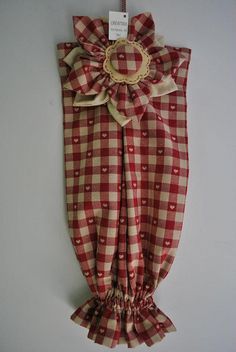 a red and white checkered cloth with a flower on the front hanging from a hook