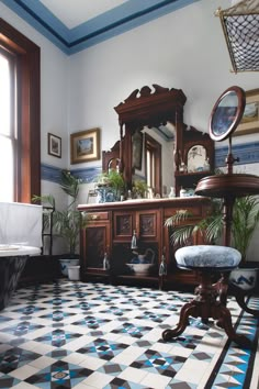 an old fashioned bathroom with blue and white tiles on the floor, potted plants