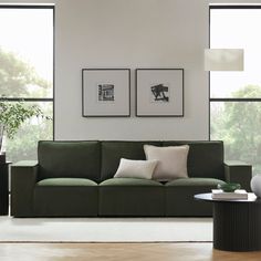 a living room with green couches and two framed pictures on the wall above them