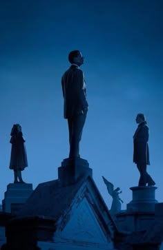 three statues on top of a building at night