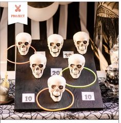 a table topped with lots of fake skulls on top of a black and white table cloth