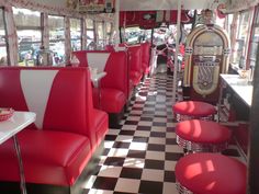 the interior of a diner car with red and white booths, checkered flooring