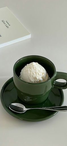 a green bowl filled with white powder on top of a saucer next to two spoons