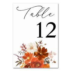 a table number card with an orange and white flower arrangement on the front, in black ink