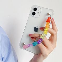 a woman holding an iphone case with beads and charms attached to the back of it