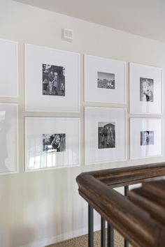 a bunch of pictures hanging on the wall above a banister in a living room