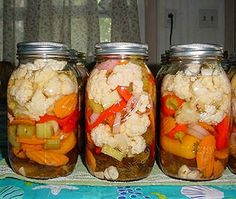 four jars filled with different types of vegetables