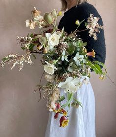 a woman holding a bouquet of flowers in her hands