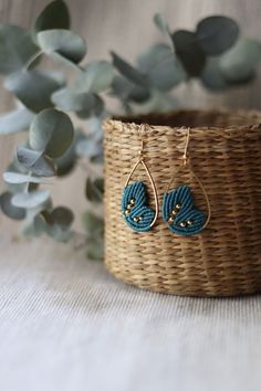 a basket with some plants in it and two blue beads hanging from the side of it