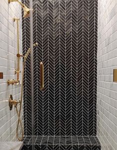 a bathroom with black and white tiles, gold fixtures and a shower head