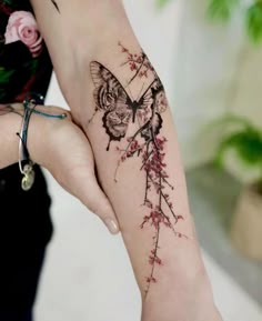 a woman's arm with a butterfly and flower tattoo on the left side of her body