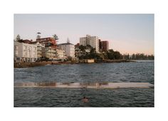 a body of water with houses in the background and buildings on the shore behind it