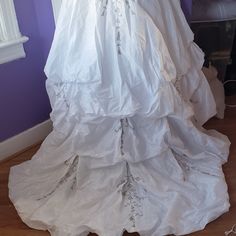 a white wedding dress is on display in front of a purple wall and wooden floor