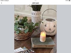 a table topped with books and candles next to a white vase filled with greenery