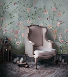 a chair sitting in front of a wall with flowers and birds painted on the walls