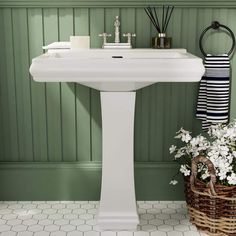 a white pedestal sink sitting next to a green wall