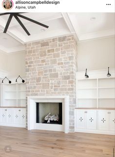 an empty living room with white cabinets and a brick fireplace in the center, surrounded by wood flooring