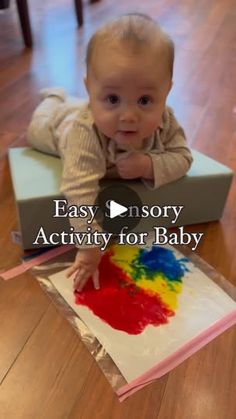 a baby sitting on top of a box with paint