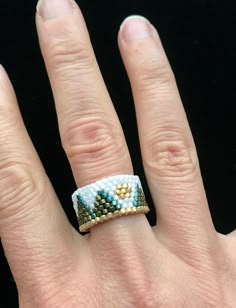 a woman's hand with a ring on it that is made out of beads