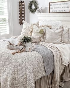 a white bed with pillows and blankets on top of it next to a window sill