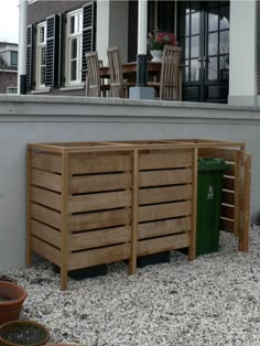 a wooden bench sitting on top of a gravel covered ground next to potted plants