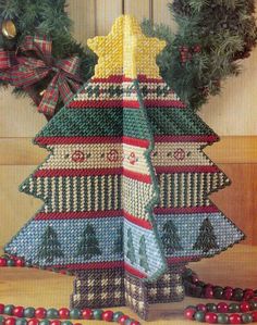 a crocheted christmas tree sitting on top of a wooden table next to beads