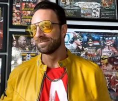 a man in yellow jacket and sunglasses standing next to wall with comic books on it