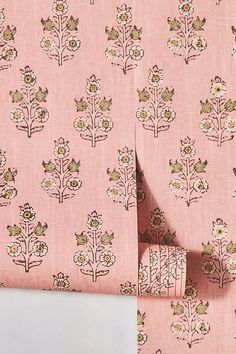 a pink wallpaper with small flowers and leaves on it's side, next to a pair of scissors