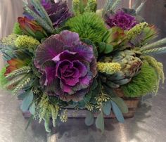 purple and green flowers in a basket on a table