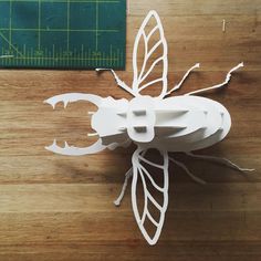 a paper cut insect sitting on top of a wooden table