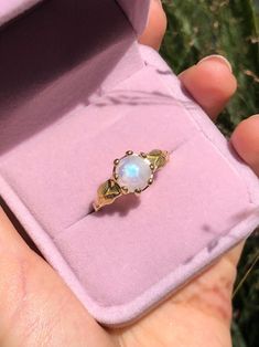 a woman's hand holding a ring with a white opal stone in it