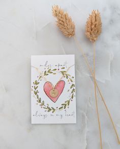 a card with a heart on it next to two dried plants