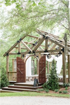 an outdoor gazebo with wooden doors and curtains