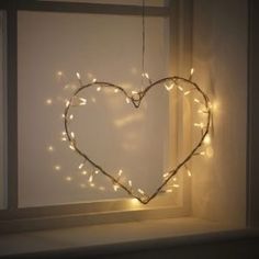 a heart shaped string light hanging from a window sill