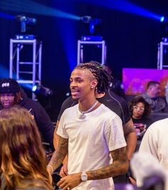 a man with dreadlocks standing in front of a group of people on stage