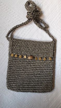 a crocheted purse is hanging on a white tablecloth with a string attached to it