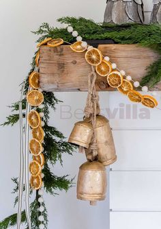 a bunch of oranges that are hanging from a wooden beam with bells attached to it