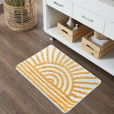 a yellow and white bathroom rug on the floor next to a wooden cabinet with drawers