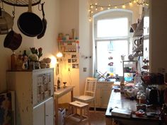 a kitchen filled with lots of clutter and cooking utensils hanging from the ceiling