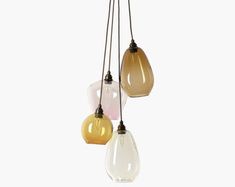 three different colored glass light bulbs hanging from a ceiling fixture in various shapes and sizes