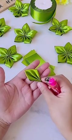 a person is making some paper flowers out of satin ribbons and ribboning them with scissors