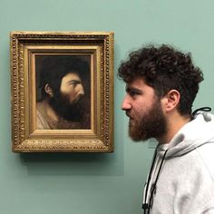 a man standing in front of a painting on the wall with his head tilted to the side