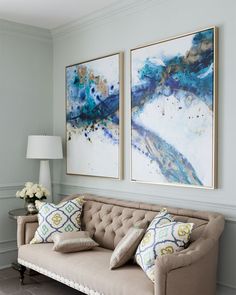 a living room with two paintings on the wall and couches in front of them