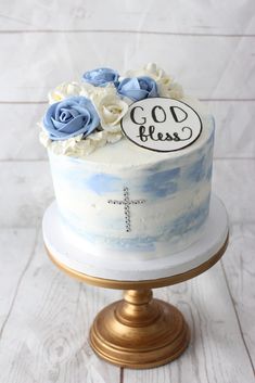 a blue and white cake sitting on top of a wooden table next to a cross