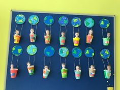 a bulletin board with paper mache people hanging from the hooks and cups on them